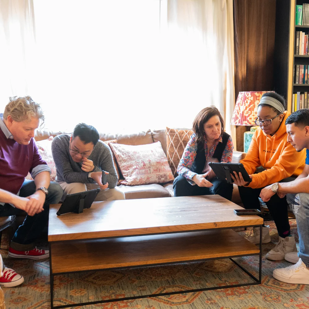 a group of people sitting on a couch looking at a tablet