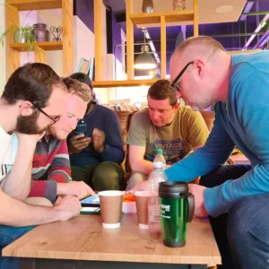 a group of men sitting around a table looking at a tablet